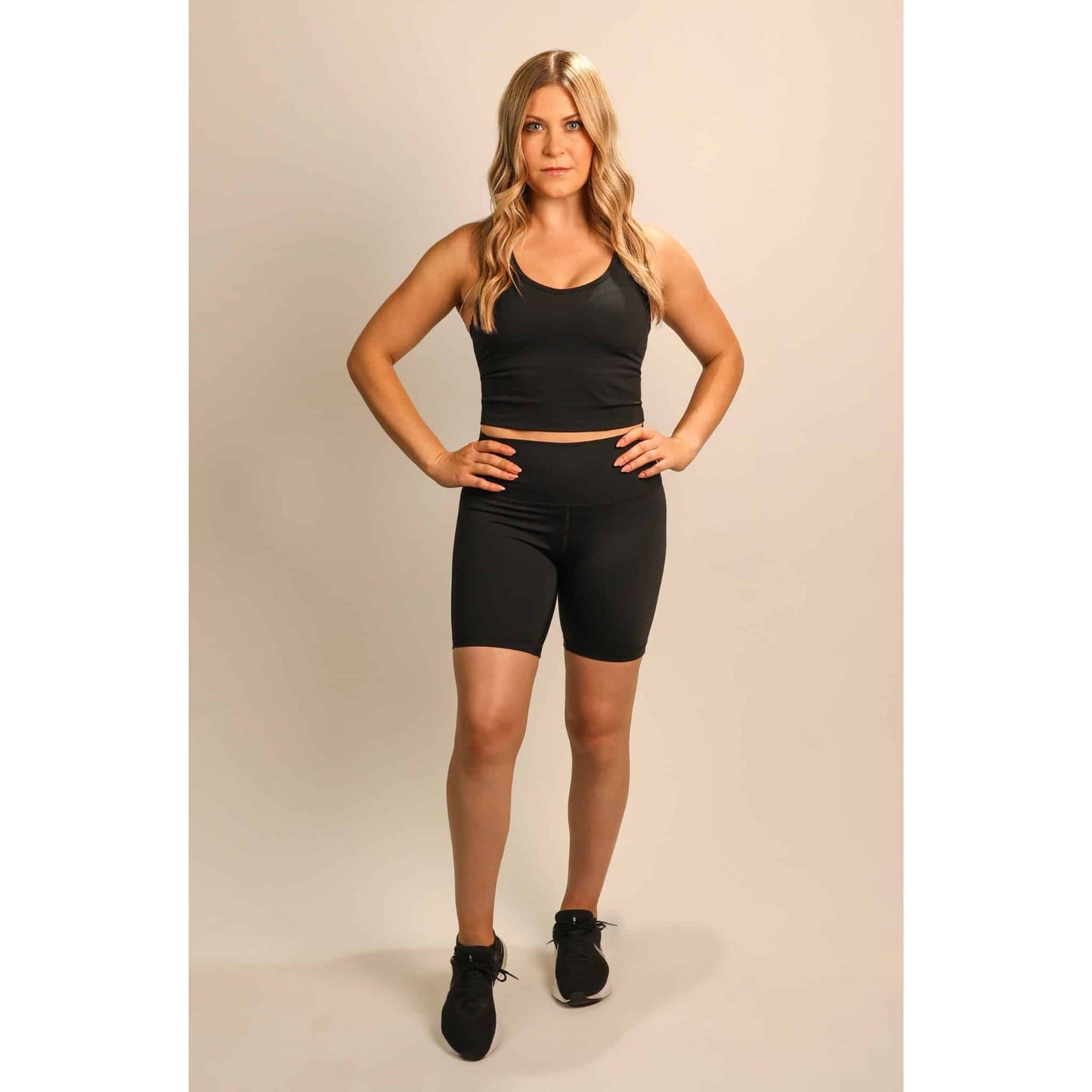 Personal trainer posing forward wearing black biker shorts set by Quoia activewear